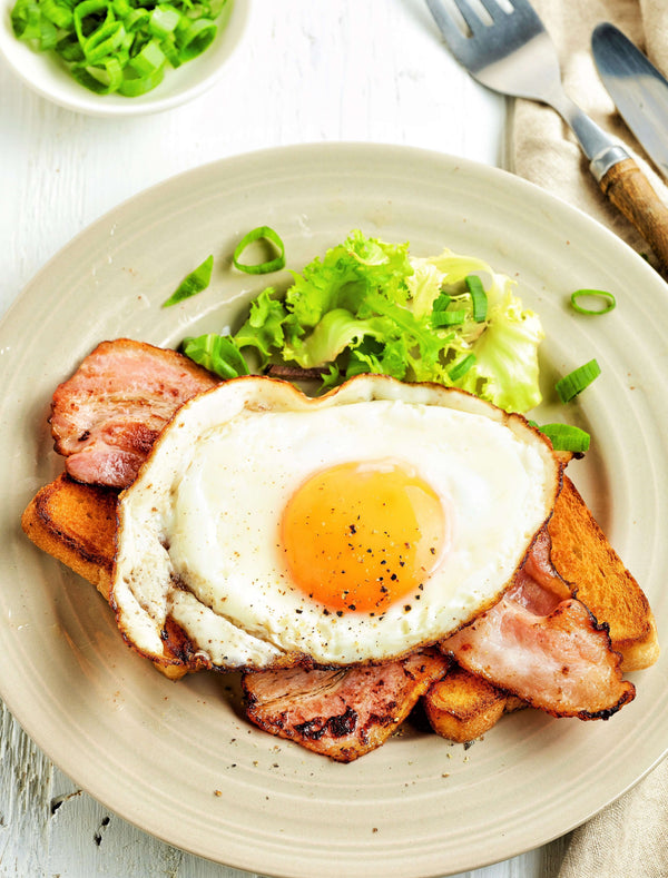 Plate of smoked bacon and onion fried egg served on toast with fresh greens, showcasing 5 Easy Ways to Use Smoked Bacon and Onion Sea Salt in Recipes.