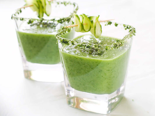 Refreshing Avocado Gazpacho served in glasses garnished with cucumber slices and herb rims.