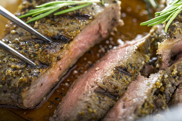Smoked Bacon Chipotle Steak sliced with herbs, showcasing tender juicy texture and flavorful seasoning.